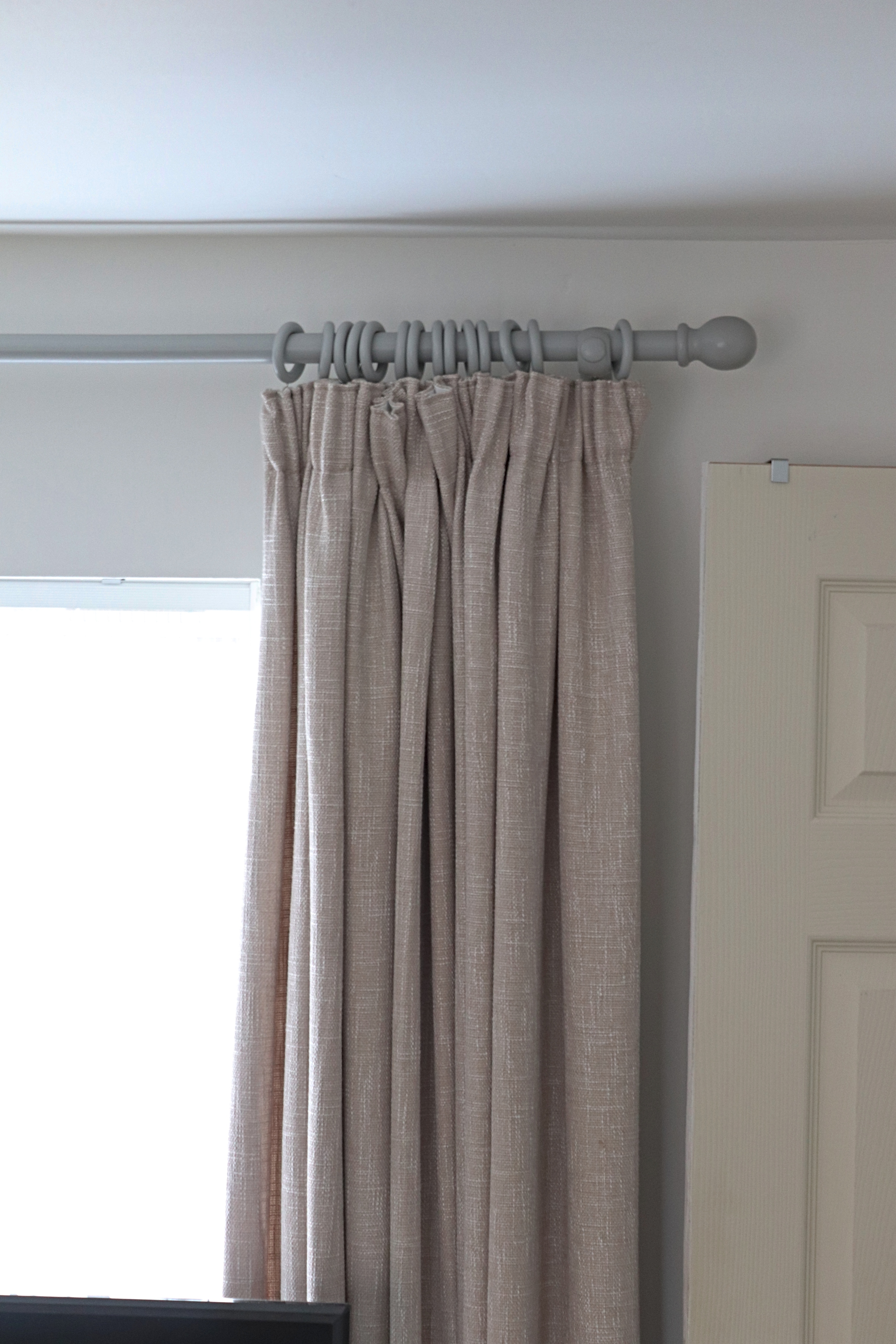 a grey curtain pole with natural curtains